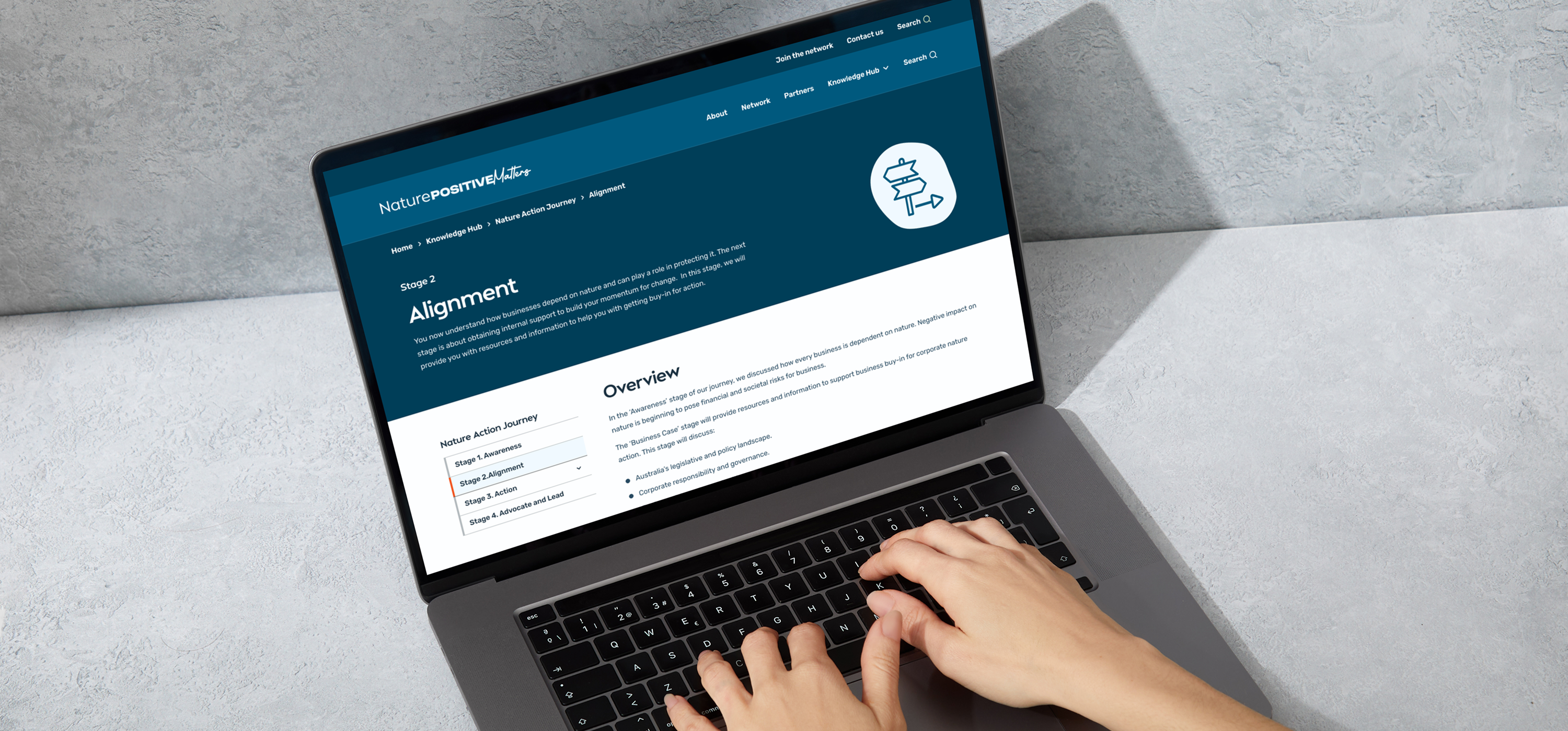 A person typing on a laptop displaying the Knowledge Hub's Alignment stage page with an overview section.